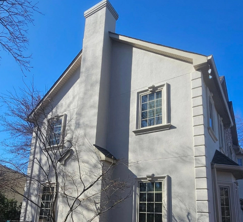 Sun shining on gray stucco-laden home in Franklin Lakes, NJ
